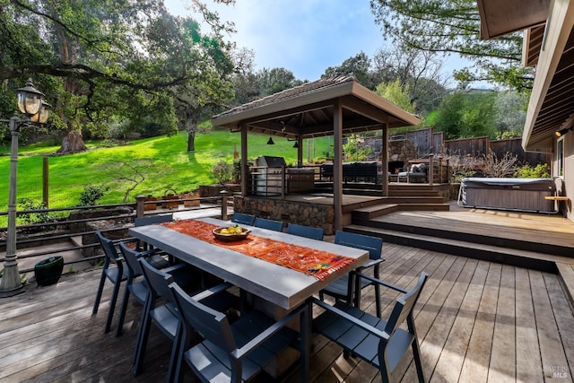 wooden deck featuring outdoor dining space, fence, a hot tub, and grilling area