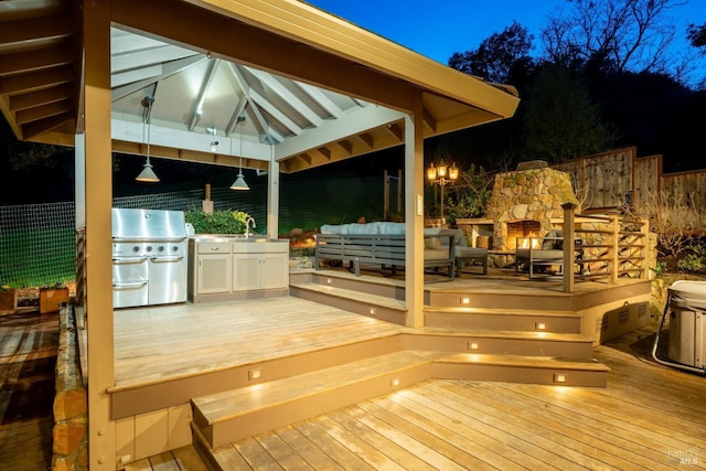 wooden terrace featuring a sink, fence, a gazebo, grilling area, and an outdoor living space with a fireplace