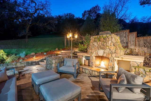 view of patio / terrace with fence, a deck, and an outdoor living space with a fireplace