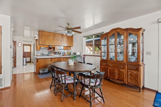 dining space featuring light wood-type flooring, visible vents, ceiling fan, and baseboards