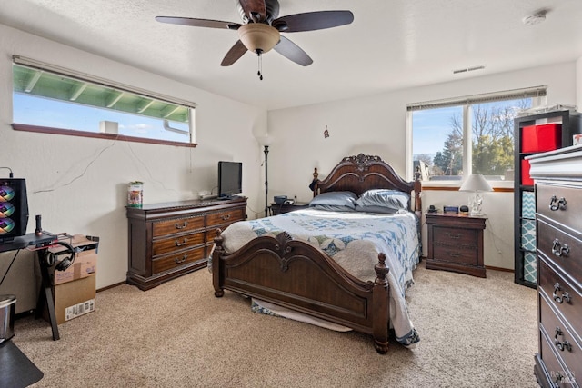 bedroom featuring baseboards, multiple windows, visible vents, and a ceiling fan