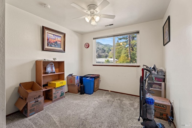 interior space featuring ceiling fan, visible vents, baseboards, and light colored carpet