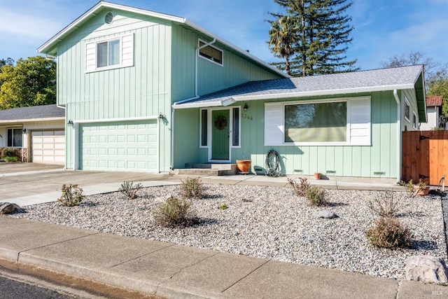 traditional-style house featuring a shingled roof, concrete driveway, fence, and a garage