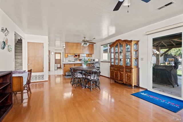 dining space featuring visible vents, stairway, a ceiling fan, a textured ceiling, and light wood-type flooring