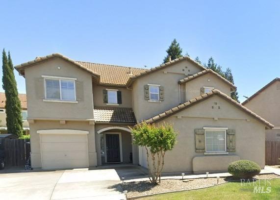 mediterranean / spanish-style house featuring fence, a tiled roof, concrete driveway, stucco siding, and an attached garage