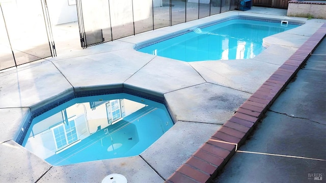 outdoor pool featuring an in ground hot tub and a patio area