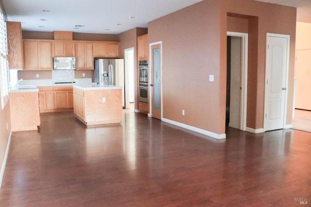 kitchen with light brown cabinetry, stainless steel appliances, light countertops, decorative backsplash, and dark wood-style flooring