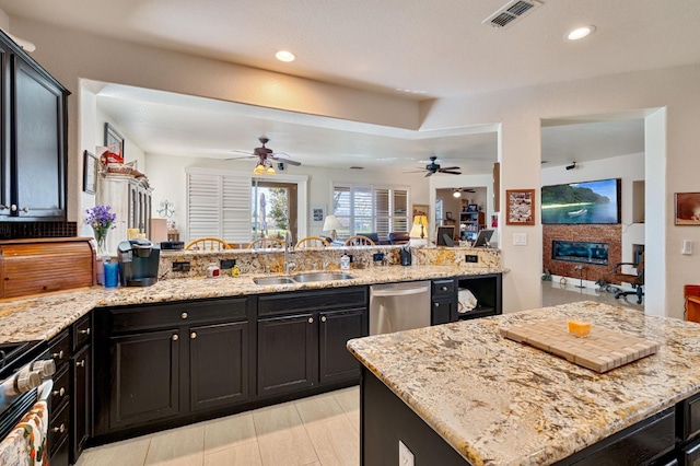 kitchen with visible vents, light stone counters, appliances with stainless steel finishes, a peninsula, and a sink