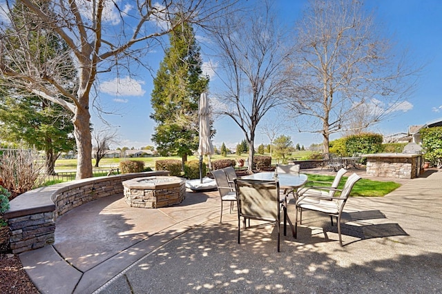 view of patio with outdoor dining area, a fire pit, and fence