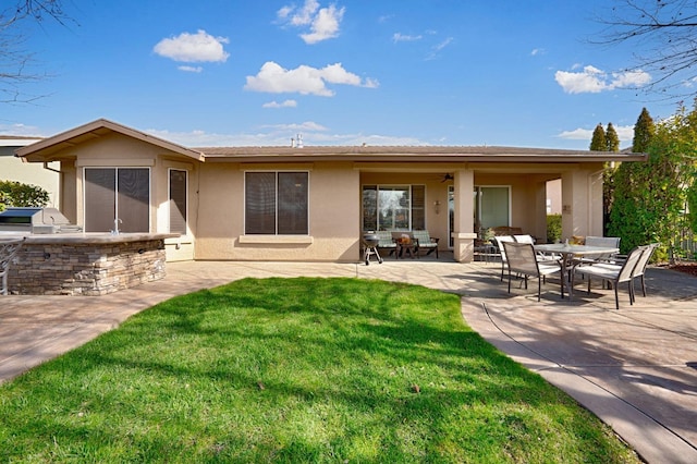 rear view of house with stucco siding, a lawn, area for grilling, a patio, and ceiling fan