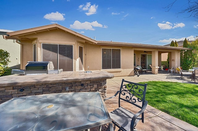 rear view of property with stucco siding, a patio, a yard, and exterior kitchen