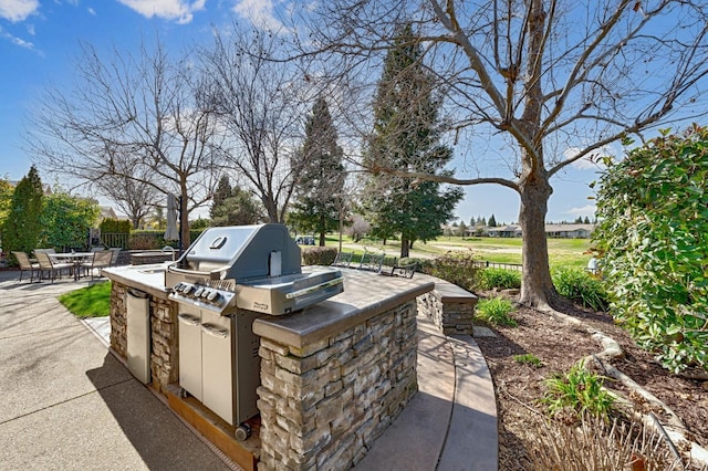 view of patio / terrace featuring area for grilling, outdoor dining area, fence, and an outdoor kitchen