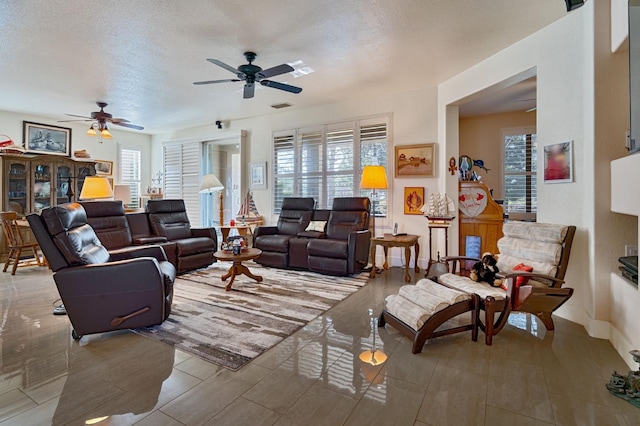 living room with visible vents, a healthy amount of sunlight, a textured ceiling, and ceiling fan