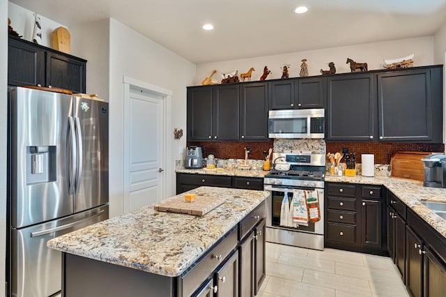 kitchen with a center island, decorative backsplash, stainless steel appliances, and light stone countertops