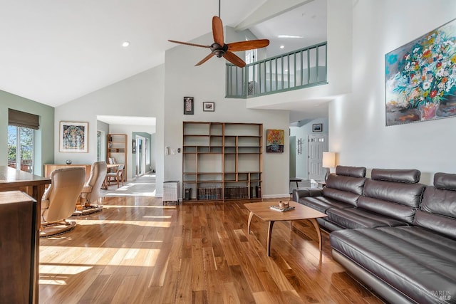 living area with high vaulted ceiling, baseboards, a ceiling fan, and wood finished floors