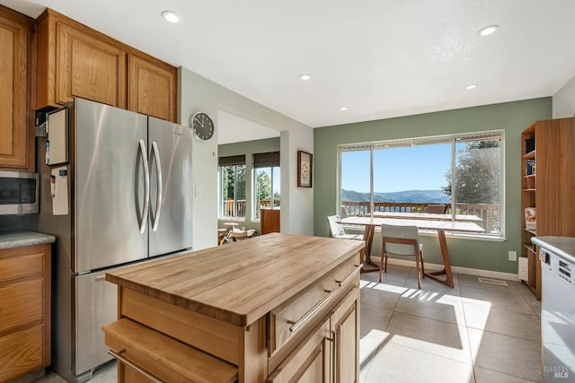 kitchen with light tile patterned floors, appliances with stainless steel finishes, a mountain view, and brown cabinets