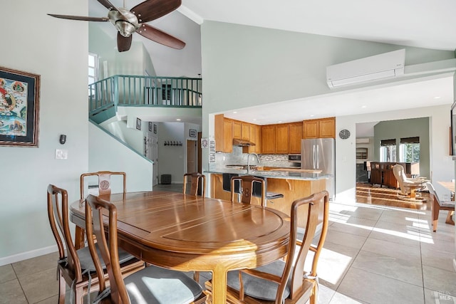 dining room with baseboards, light tile patterned flooring, a high ceiling, and a wall mounted AC