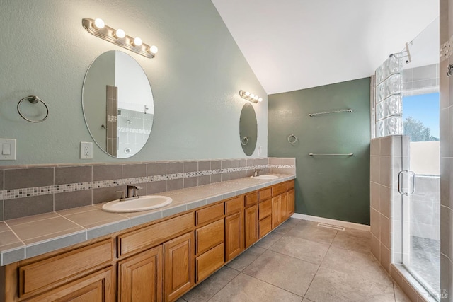 bathroom with lofted ceiling, double vanity, a sink, and tile patterned floors