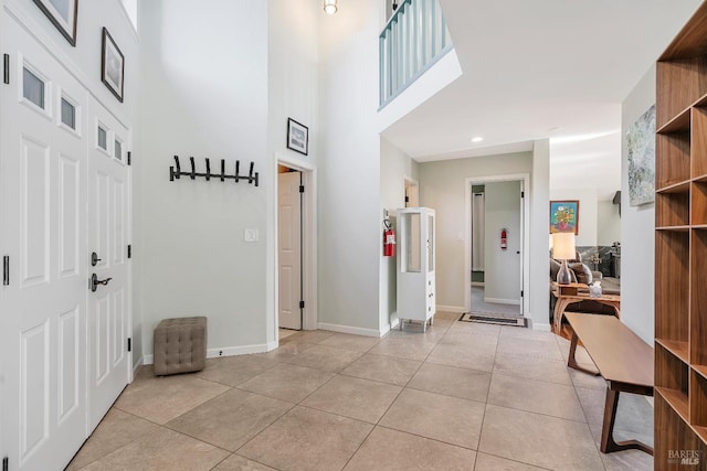 foyer entrance with a high ceiling, light tile patterned flooring, baseboards, and recessed lighting