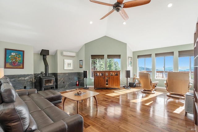 living room featuring lofted ceiling, a wood stove, light wood-style flooring, and a wall mounted AC