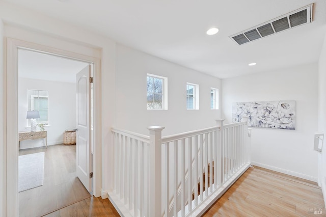 hall with recessed lighting, visible vents, an upstairs landing, light wood-type flooring, and baseboards