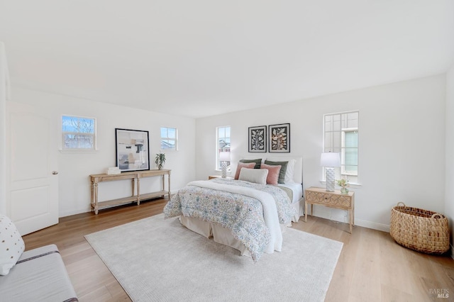 bedroom featuring light wood finished floors and baseboards