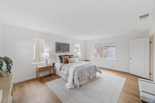 bedroom featuring visible vents, light wood-style flooring, and baseboards