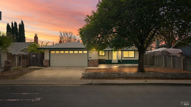 view of front of home with a garage, concrete driveway, brick siding, and fence