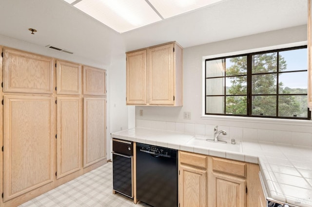 kitchen with visible vents, dishwasher, light brown cabinetry, light floors, and a sink