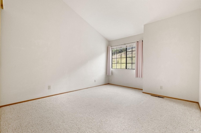 carpeted spare room with lofted ceiling, baseboards, and visible vents