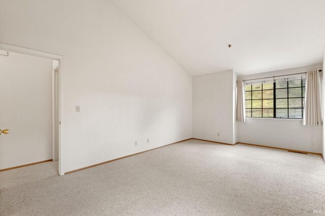 carpeted empty room featuring high vaulted ceiling, visible vents, and baseboards