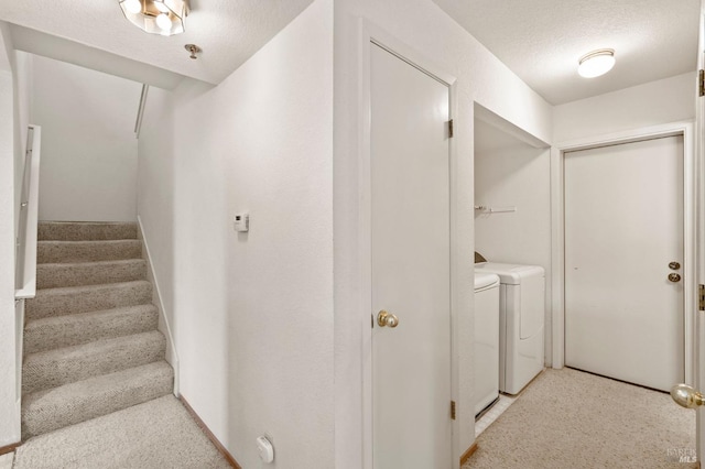 staircase with washer and clothes dryer and a textured ceiling