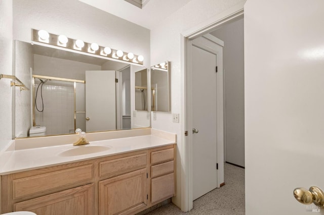 full bathroom featuring speckled floor, vanity, and an enclosed shower