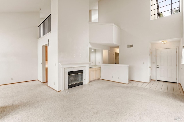 unfurnished living room featuring light tile patterned flooring, light colored carpet, a fireplace, visible vents, and baseboards