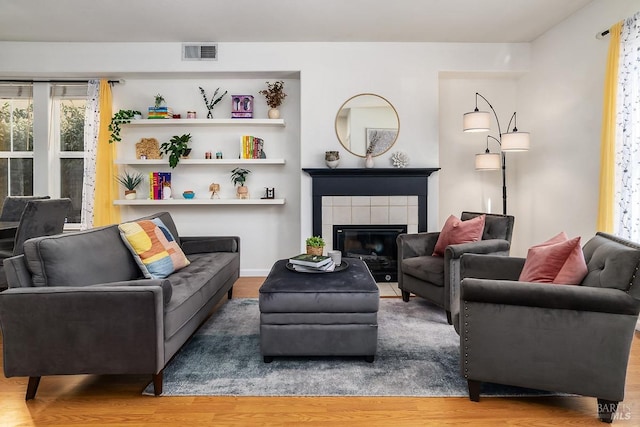 living room with a fireplace, visible vents, and wood finished floors