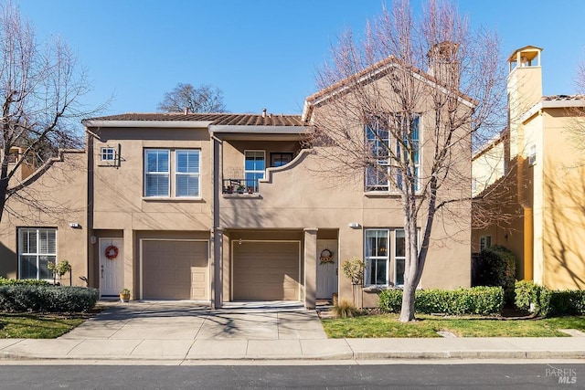 view of front of home with driveway, a tile roof, an attached garage, and stucco siding