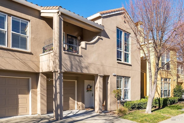 multi unit property with a garage, a tiled roof, and stucco siding