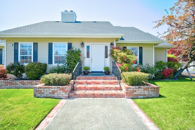 view of front of property featuring roof with shingles, a chimney, and a front yard