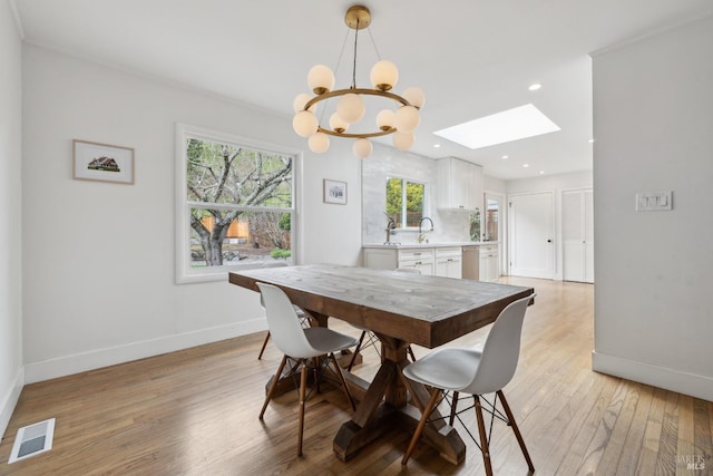 dining area featuring light wood finished floors, a skylight, baseboards, visible vents, and recessed lighting