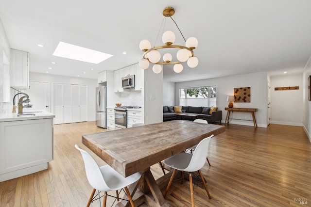 dining area featuring a chandelier, light wood finished floors, a skylight, and recessed lighting