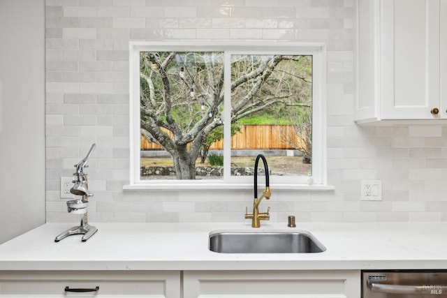 kitchen featuring dishwasher, decorative backsplash, white cabinets, and a sink