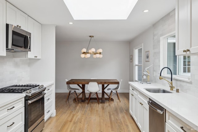 kitchen with stainless steel appliances, a sink, light countertops, and white cabinets