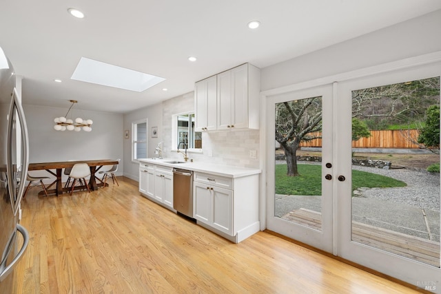 kitchen featuring light countertops, appliances with stainless steel finishes, white cabinetry, and decorative light fixtures