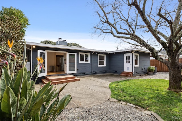 rear view of property featuring entry steps, fence, a yard, a chimney, and a patio area