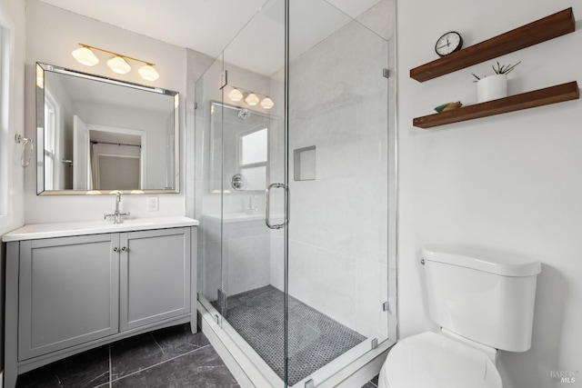 bathroom with toilet, a stall shower, and vanity