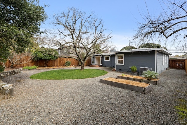 view of front of house featuring a fenced backyard, a chimney, a vegetable garden, and central air condition unit