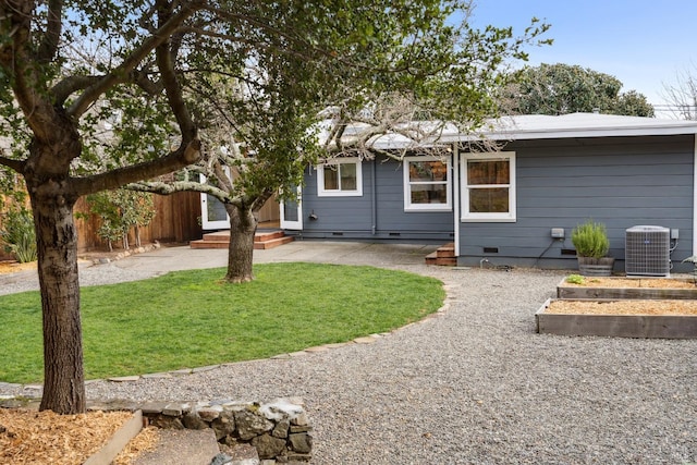 rear view of property with central air condition unit, fence, crawl space, a lawn, and a vegetable garden