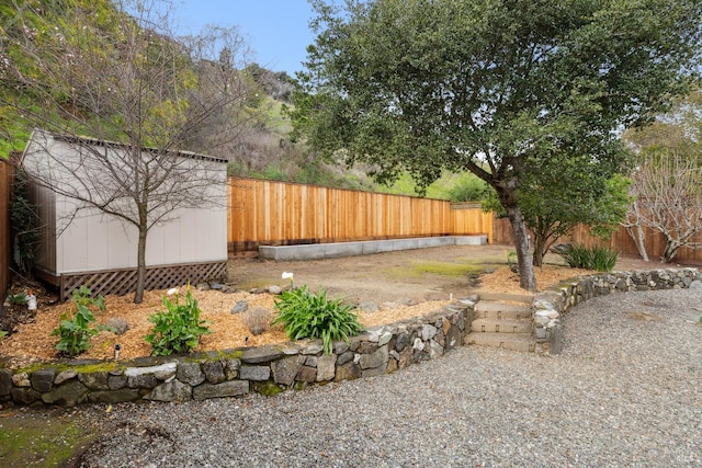 view of yard with a fenced backyard, an outdoor structure, and a storage unit