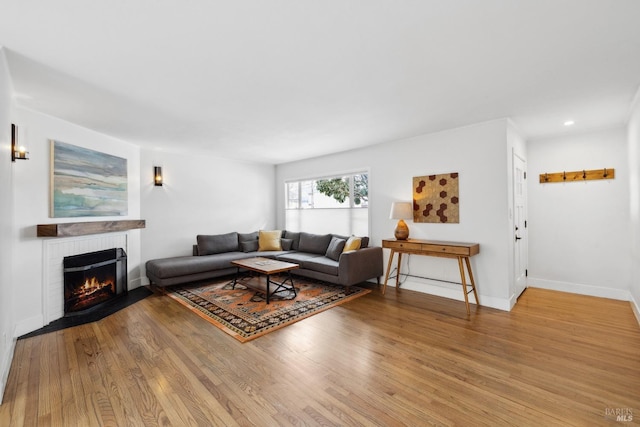 living room featuring recessed lighting, a fireplace, wood finished floors, and baseboards