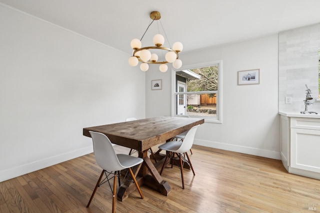 dining area with a notable chandelier, light wood-style flooring, and baseboards